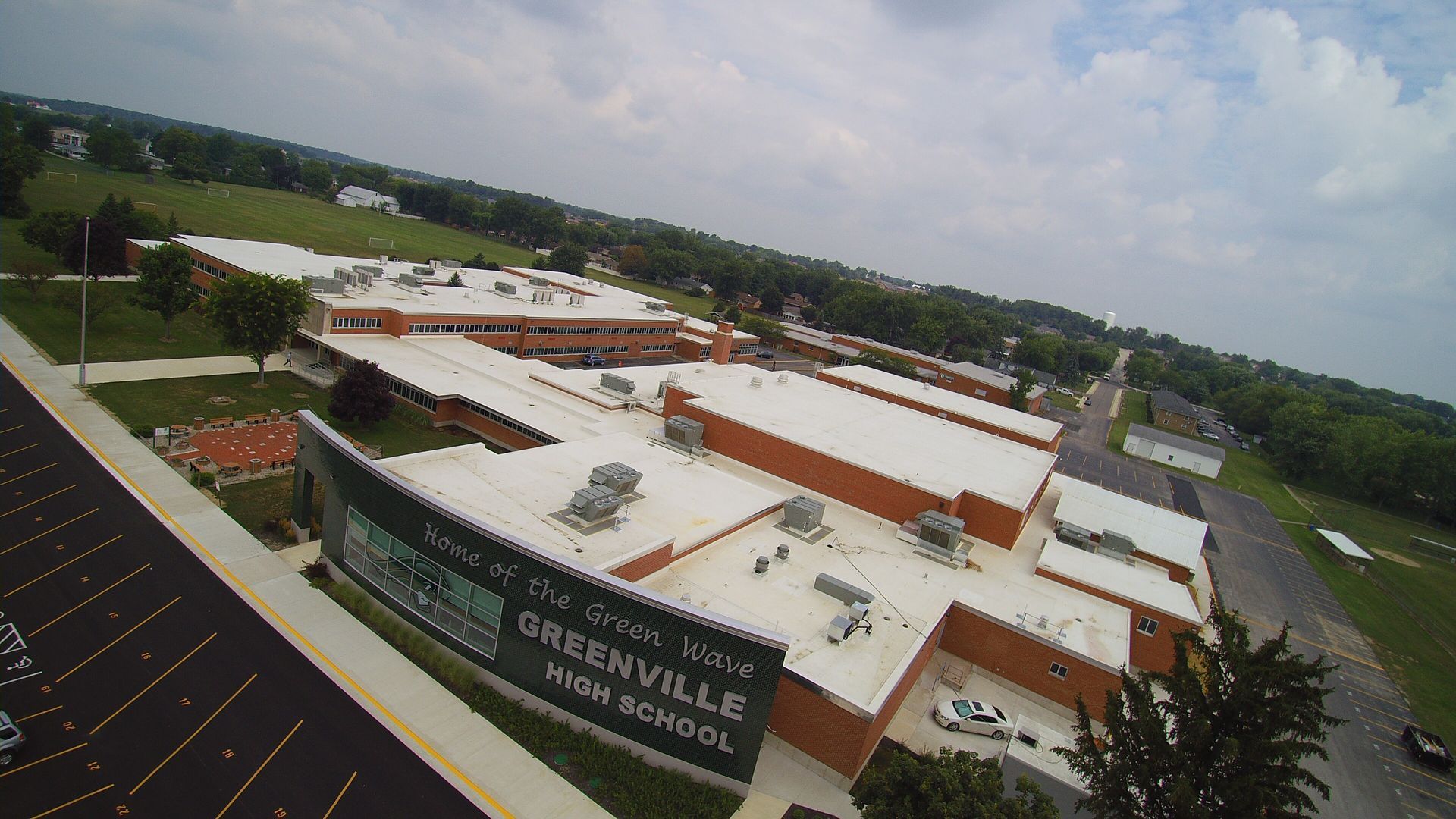 Aerial view of Greenville High School, Ohio. White and brown brick buildings with a large green sign.