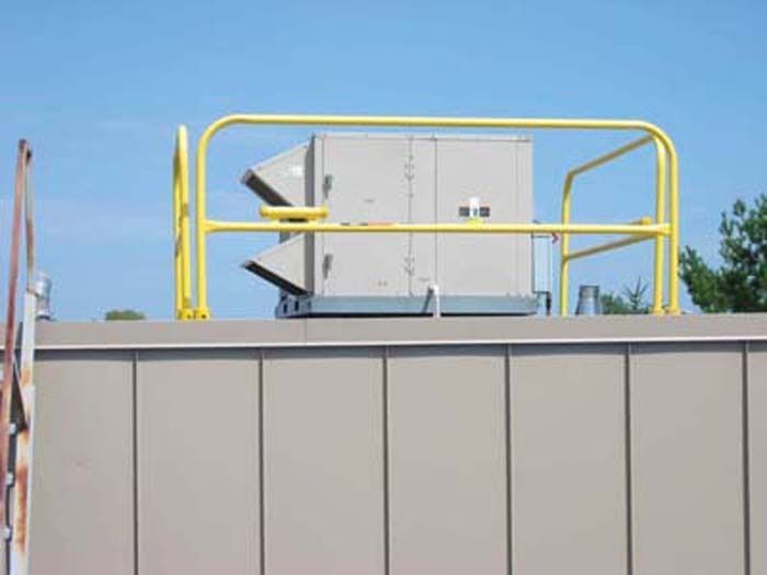 Yellow guardrail around rooftop HVAC unit.