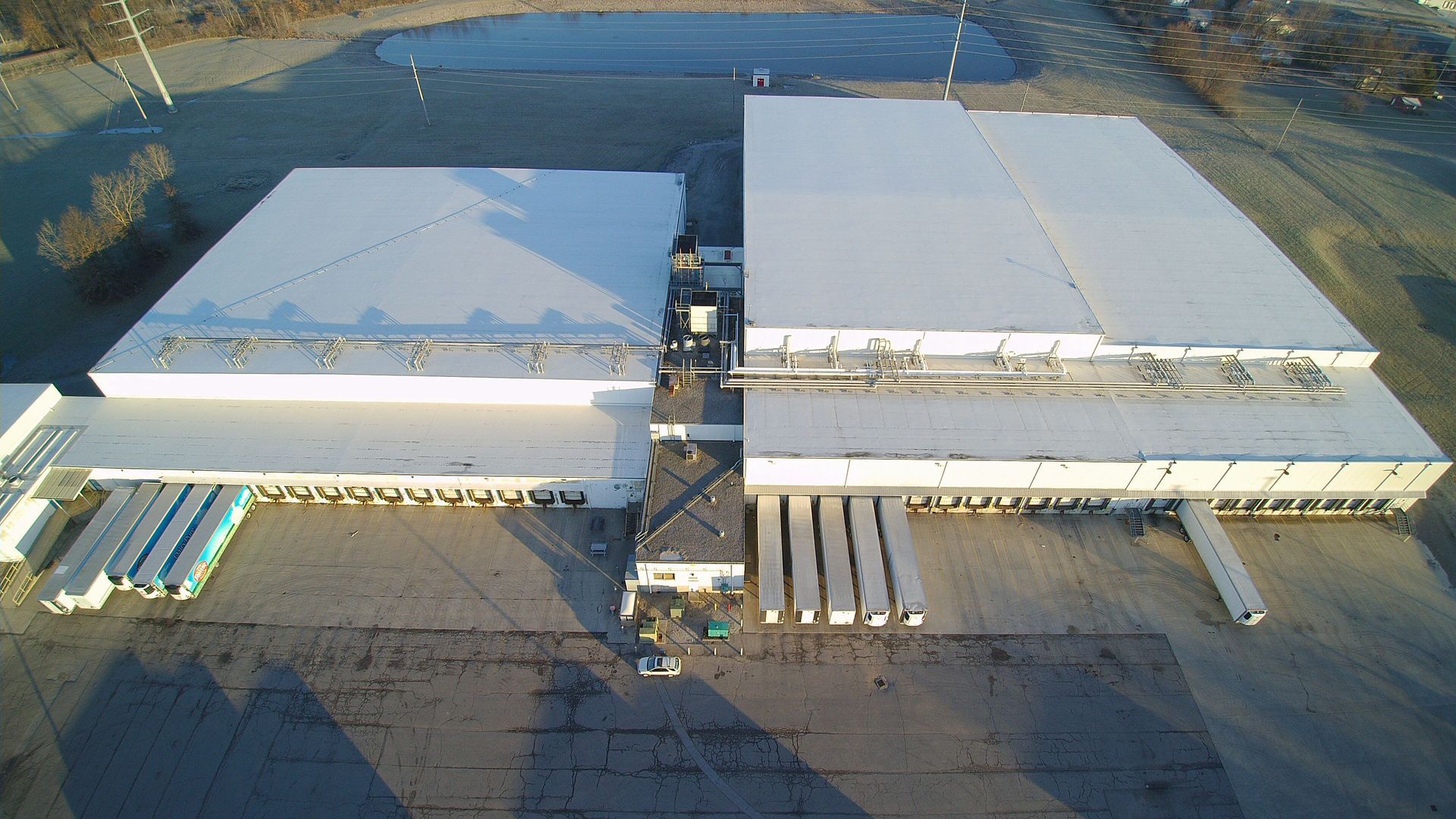Aerial view of a large industrial warehouse with loading docks and semi-trucks.
