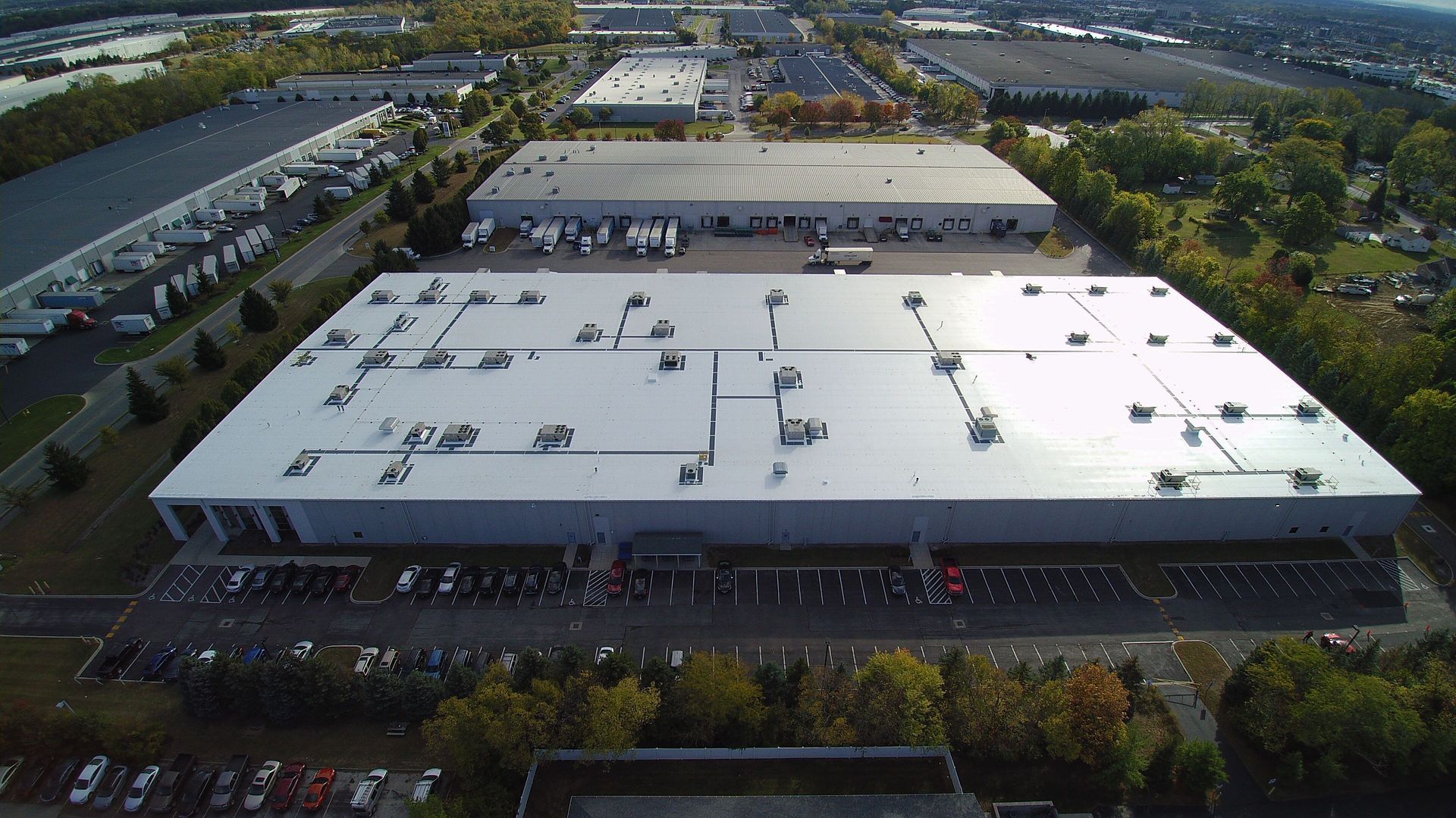 Aerial view of large industrial buildings with parking lots and trees.