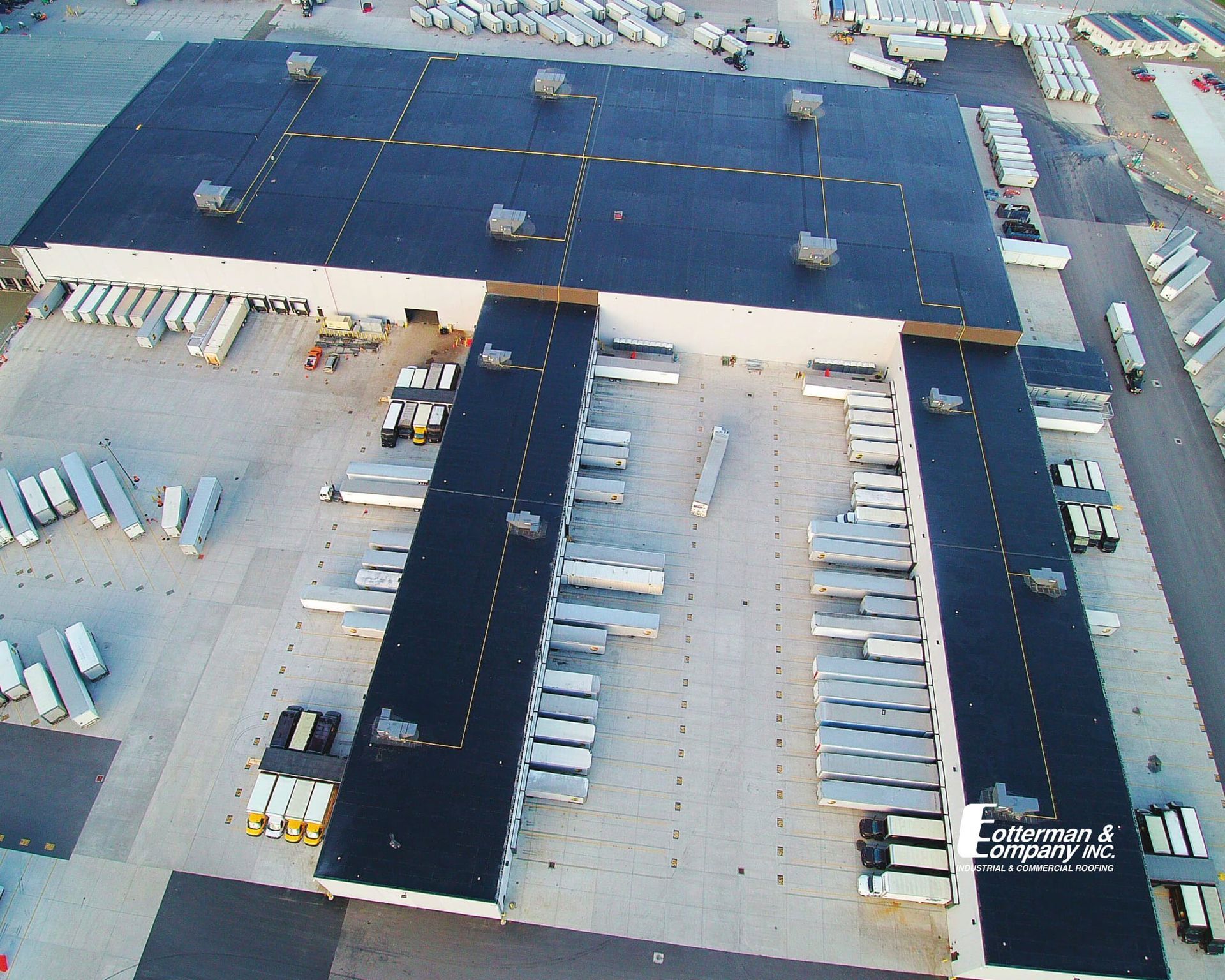 Aerial view of a large warehouse with several loading docks and parked semi-trailer trucks.