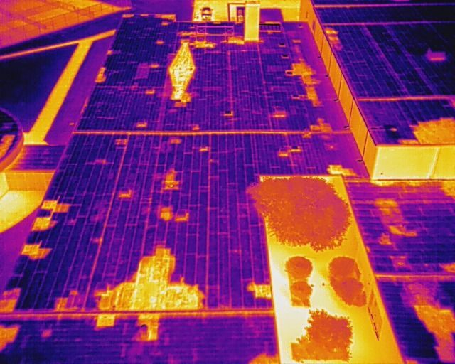 Thermal image of a rooftop solar panel array, showing heat signatures as orange and purple areas.