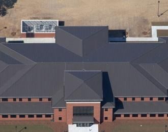 Aerial view of a building with a dark gray metal roof and red brick walls.