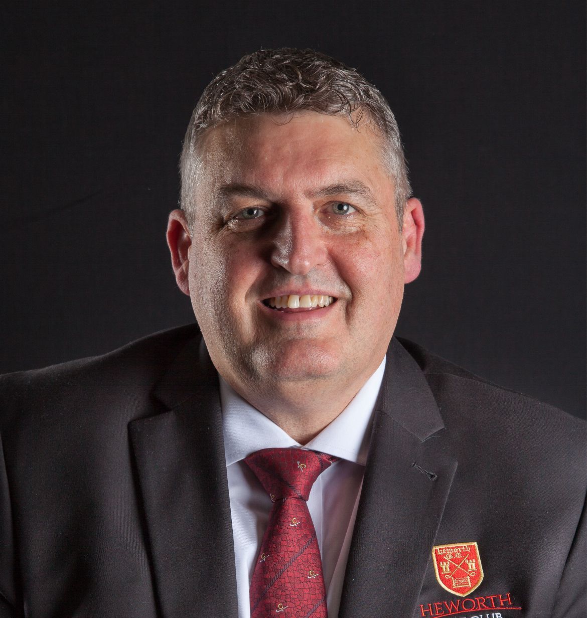 A man in a suit and tie is smiling for the camera