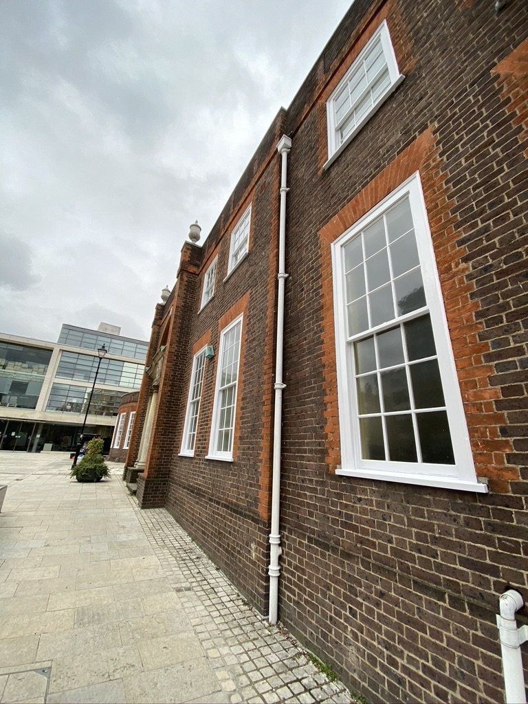 Brick building with white-framed windows, white gutter, and a cobblestone walkway.