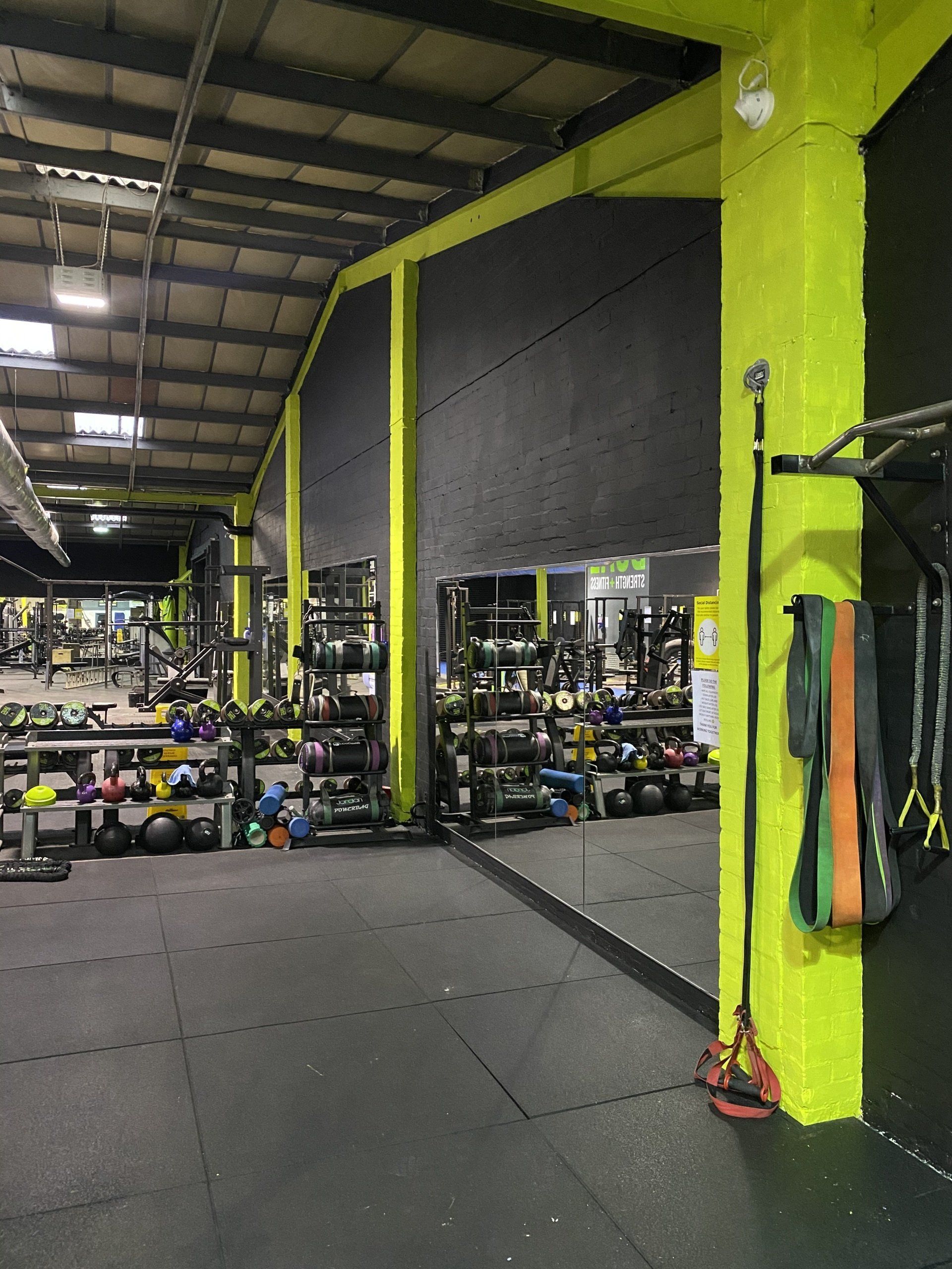 Gym interior with black flooring, yellow columns, and various exercise equipment.
