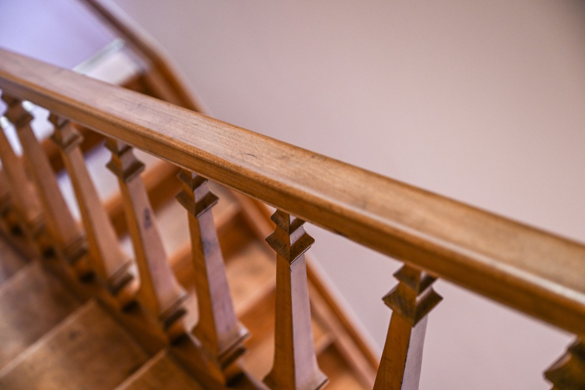 A close-up of a wooden railing leading down a flight of stairs. A close-up of a wooden railing leading down a flight of stairs.