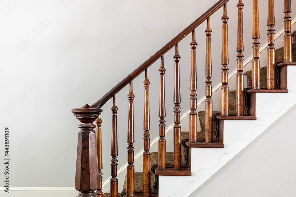 Wooden staircase railing with carved balusters against a white wall