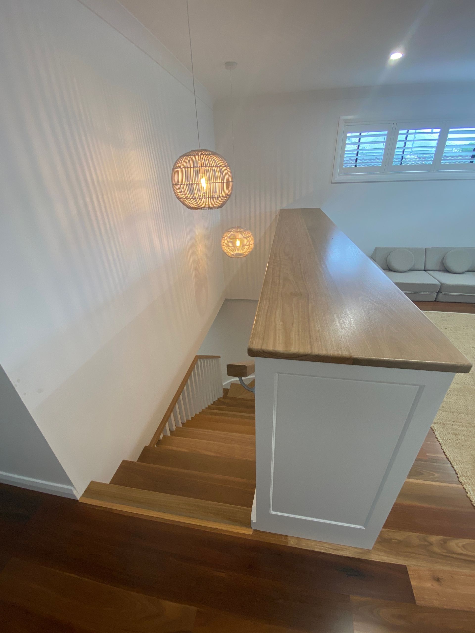 Wooden staircase with white walls, light fixtures, and a wooden banister.