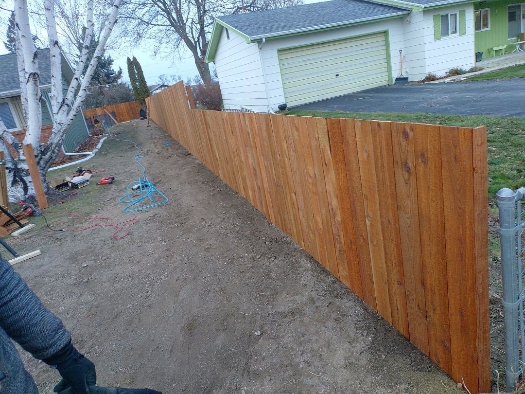 Wooden fence along a residential property, viewed from a dirt yard.