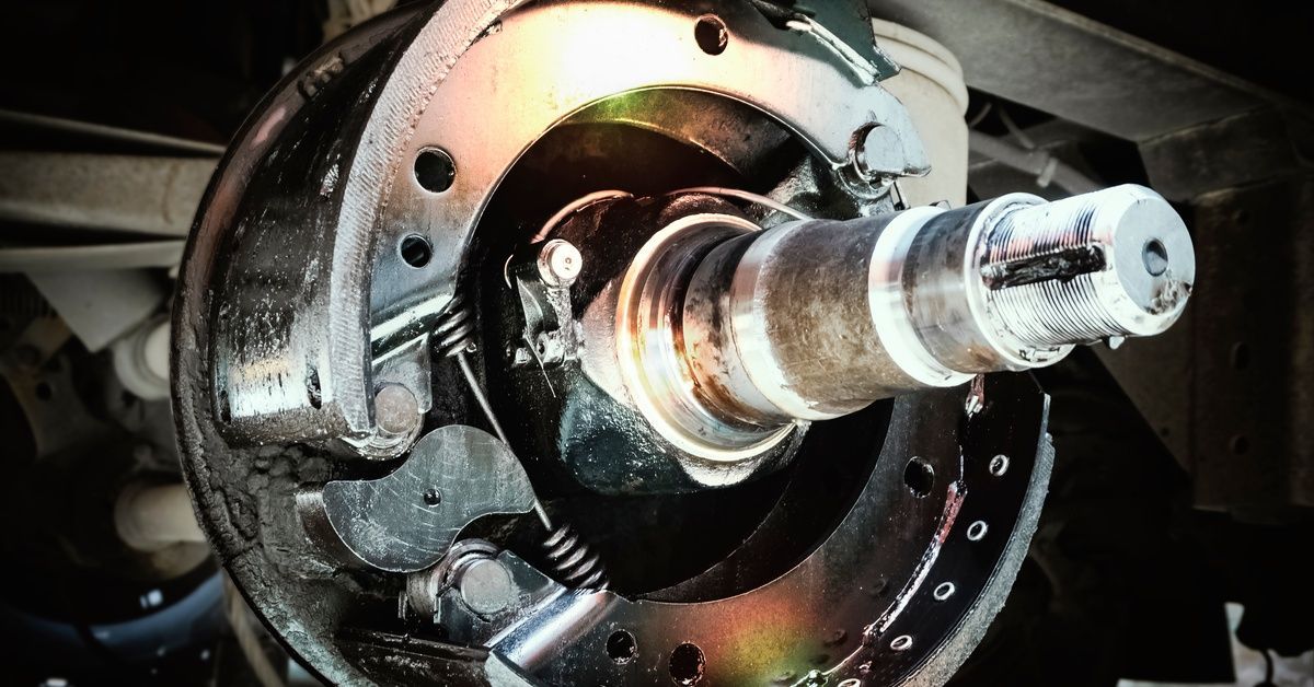 A close-up of a trailer drum brake assembly with the wheel removed, showing the axle spindle.