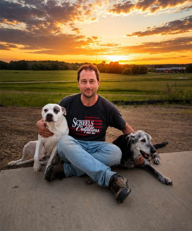 man sitting on ground with two dogs