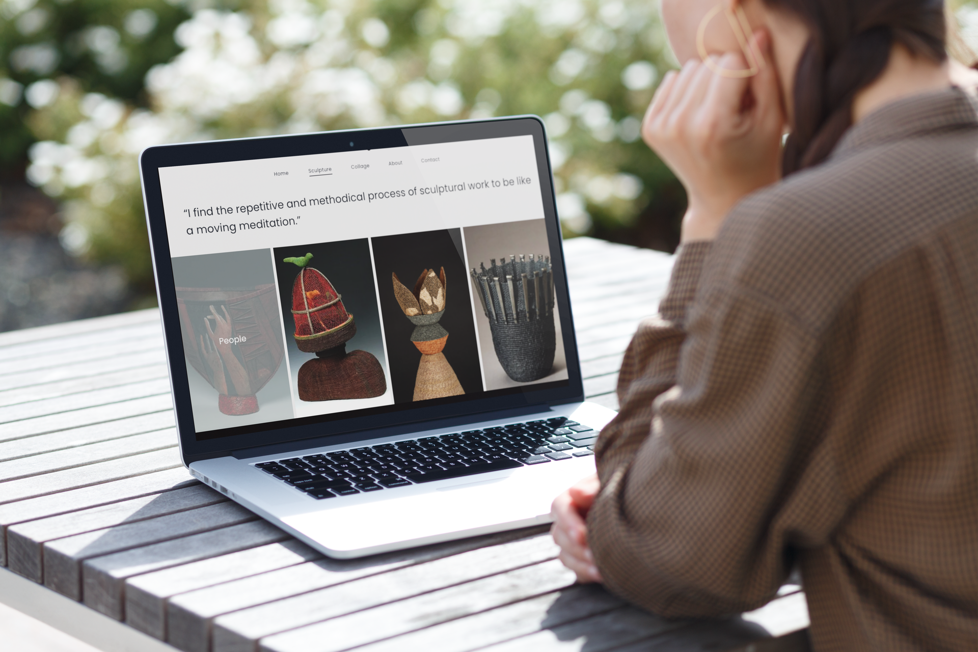 A woman is sitting at a table looking at a laptop computer.