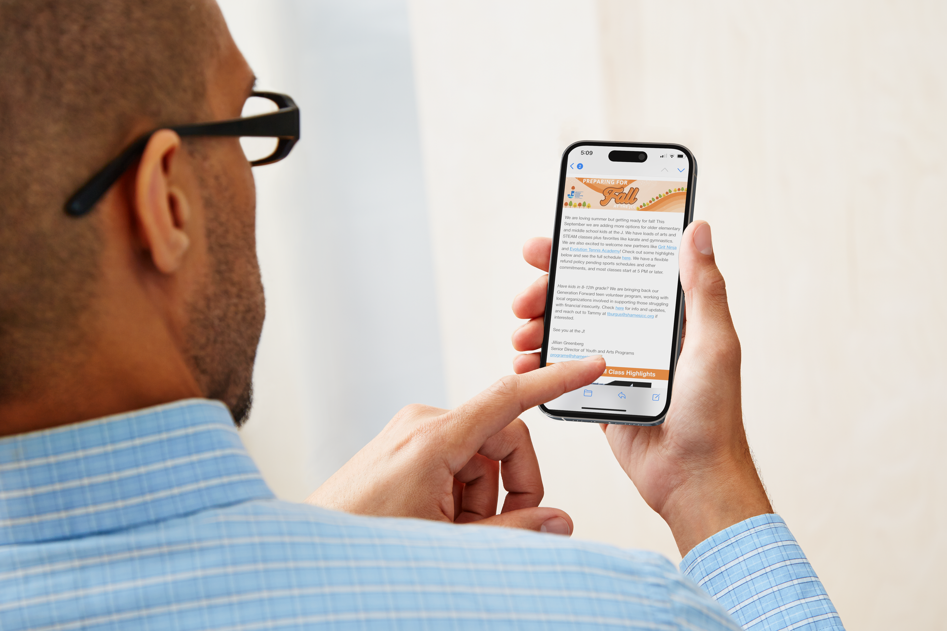 A man wearing glasses is using a cell phone.