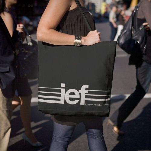 A woman is carrying a black tote bag with the word jef on it