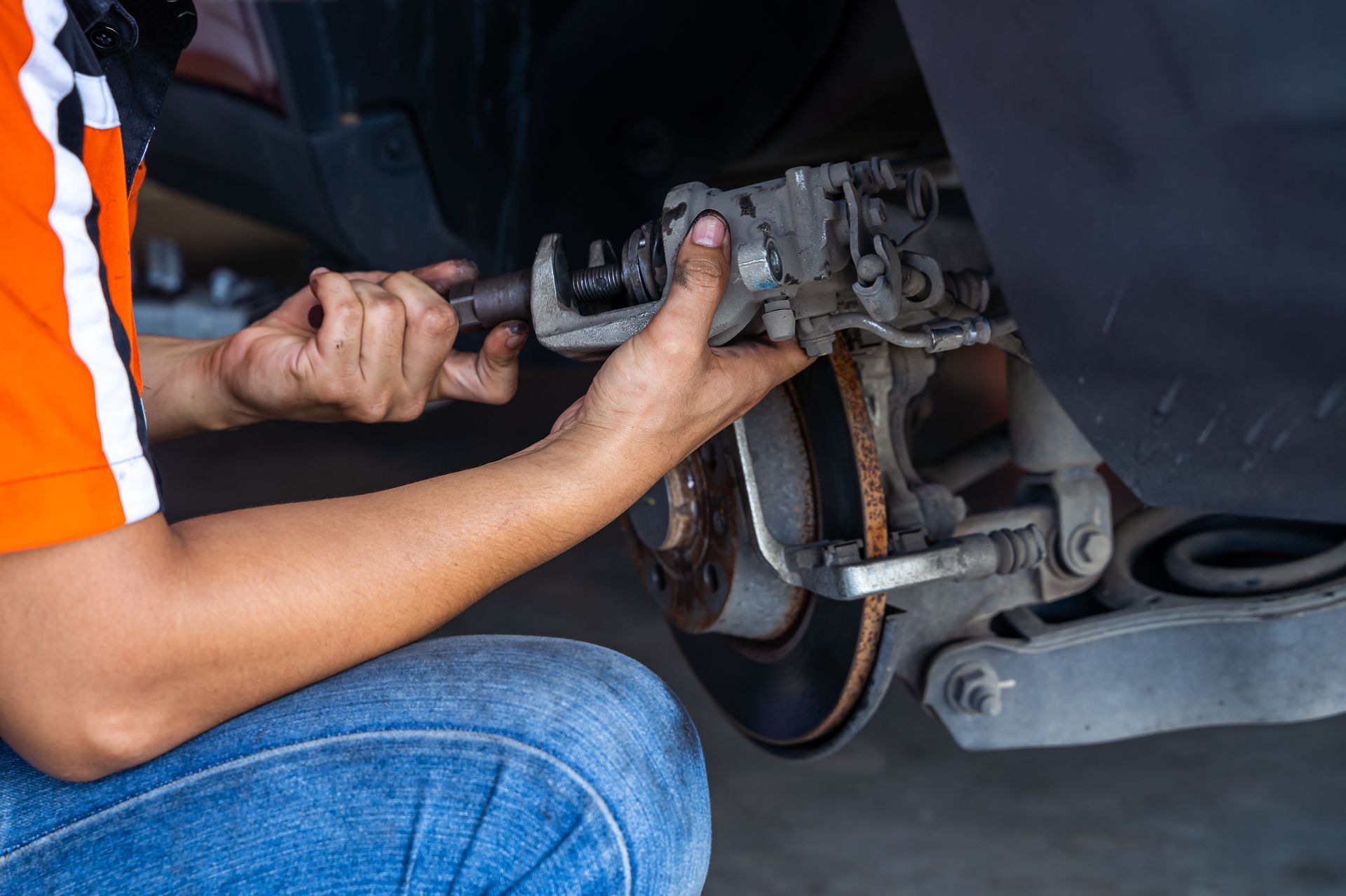 Mechanic using a tool to work on a car's brake caliper.