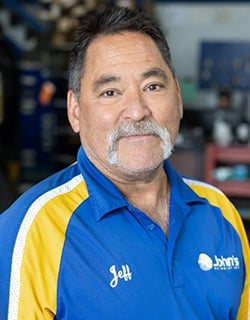 Man with a mustache wearing a blue and yellow collared shirt with