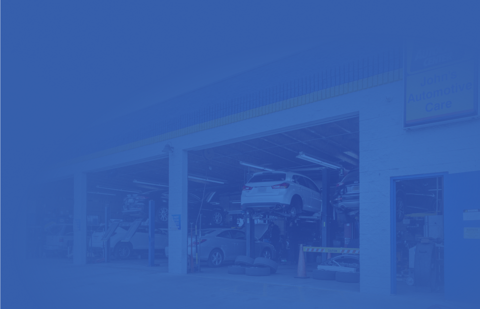 Auto repair shop with cars on lifts, inside and out. Blue tint.