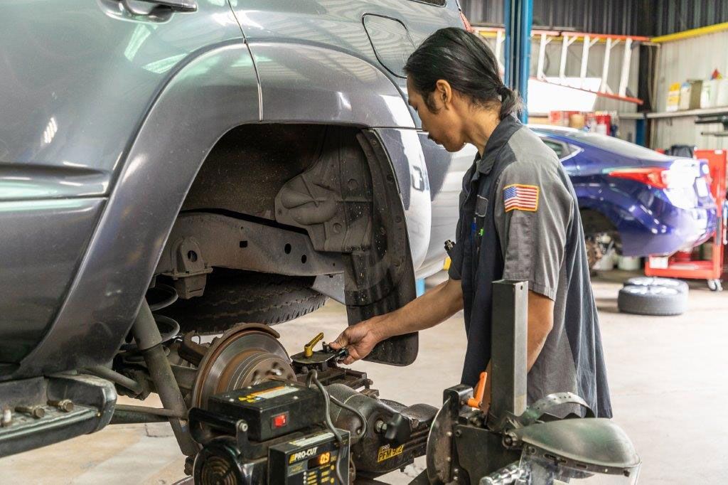 Mechanic works on a car's undercarriage in a repair shop.