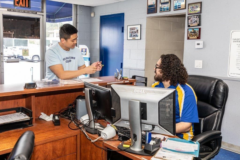 Man at front desk talking to a customer in auto repair shop.