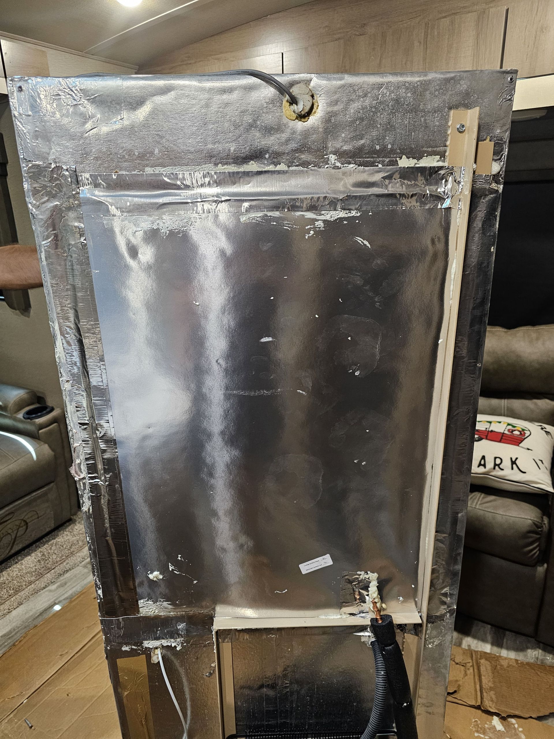 Large foil-covered rectangular panel leaning against a couch in a living room.