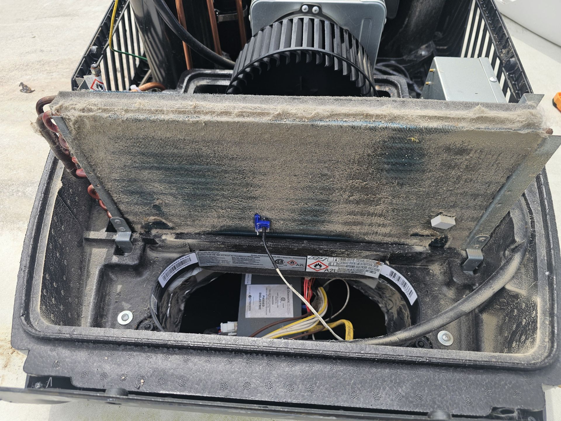 Open equipment compartment with wiring and a fan inside a metal enclosure.
