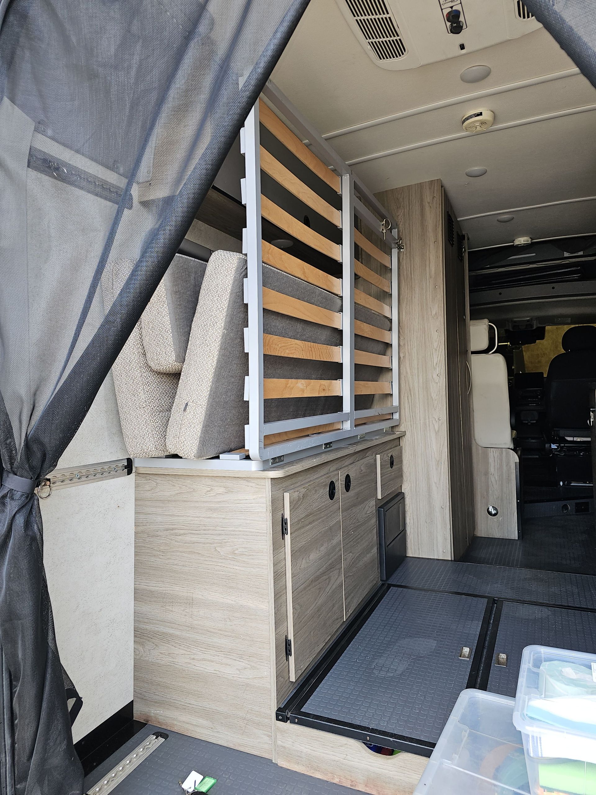 Cargo van interior with built-in wooden storage cabinets and shelves on the side wall