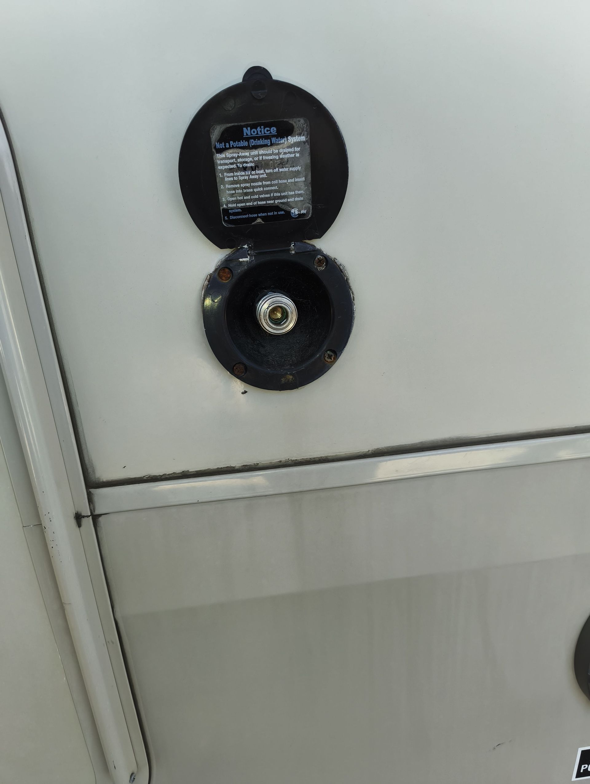 Open fuel cap on a white vehicle with the gas nozzle connector visible