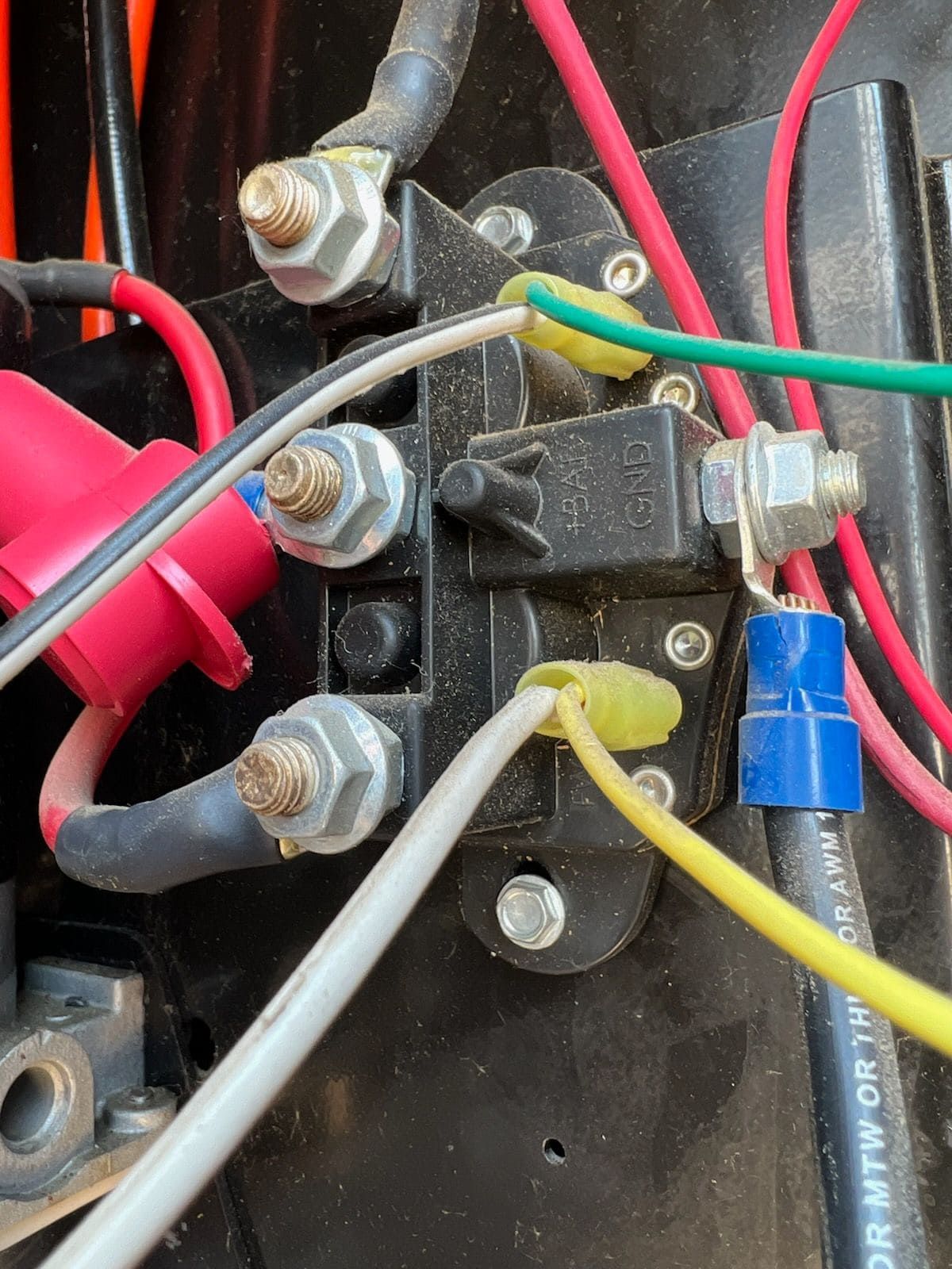 Close-up of electrical wiring on a black terminal block with red, green, yellow, and white wires.