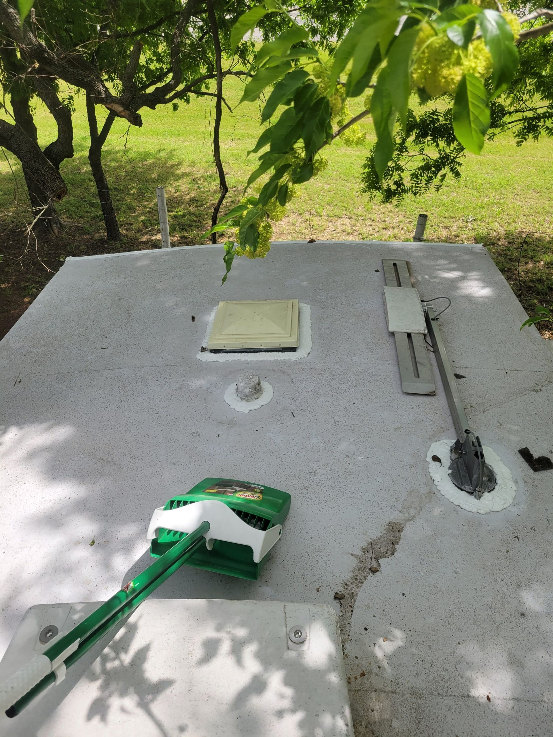 Green tool on a white utility box outdoors under tree shade