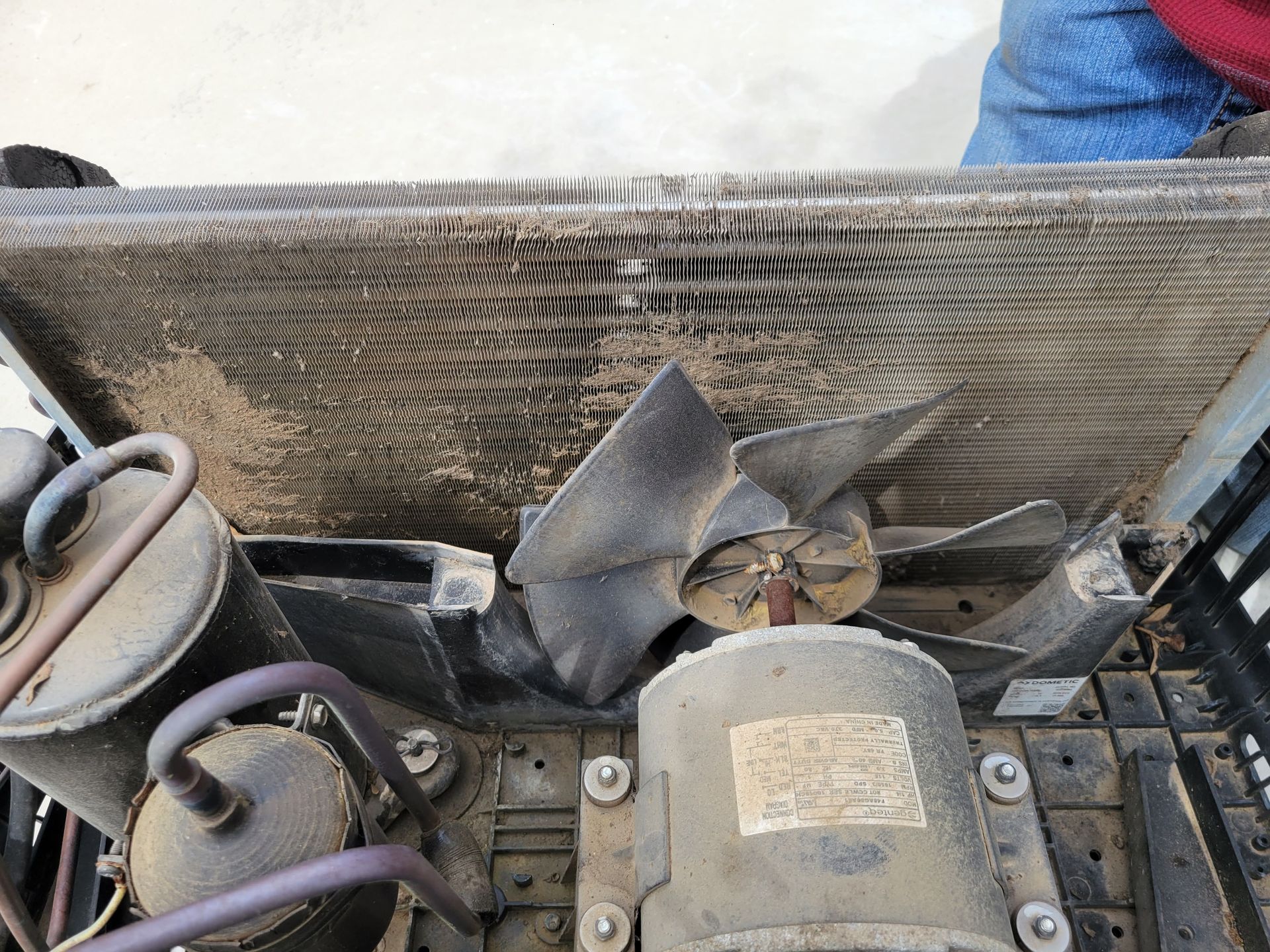 Close-up of a dusty engine with a fan, radiator, and purple hoses inside a vehicle compartment