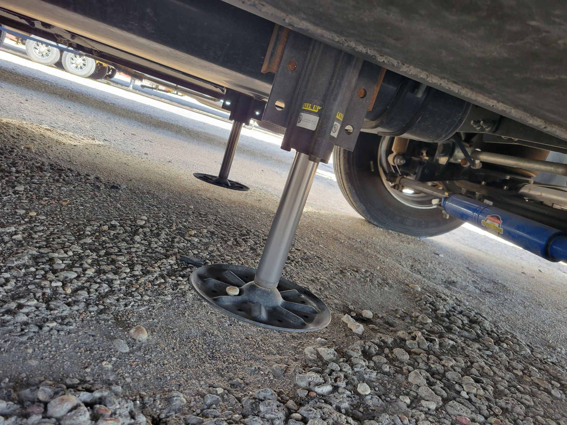 Trailer jack stand on gravel under a parked vehicle