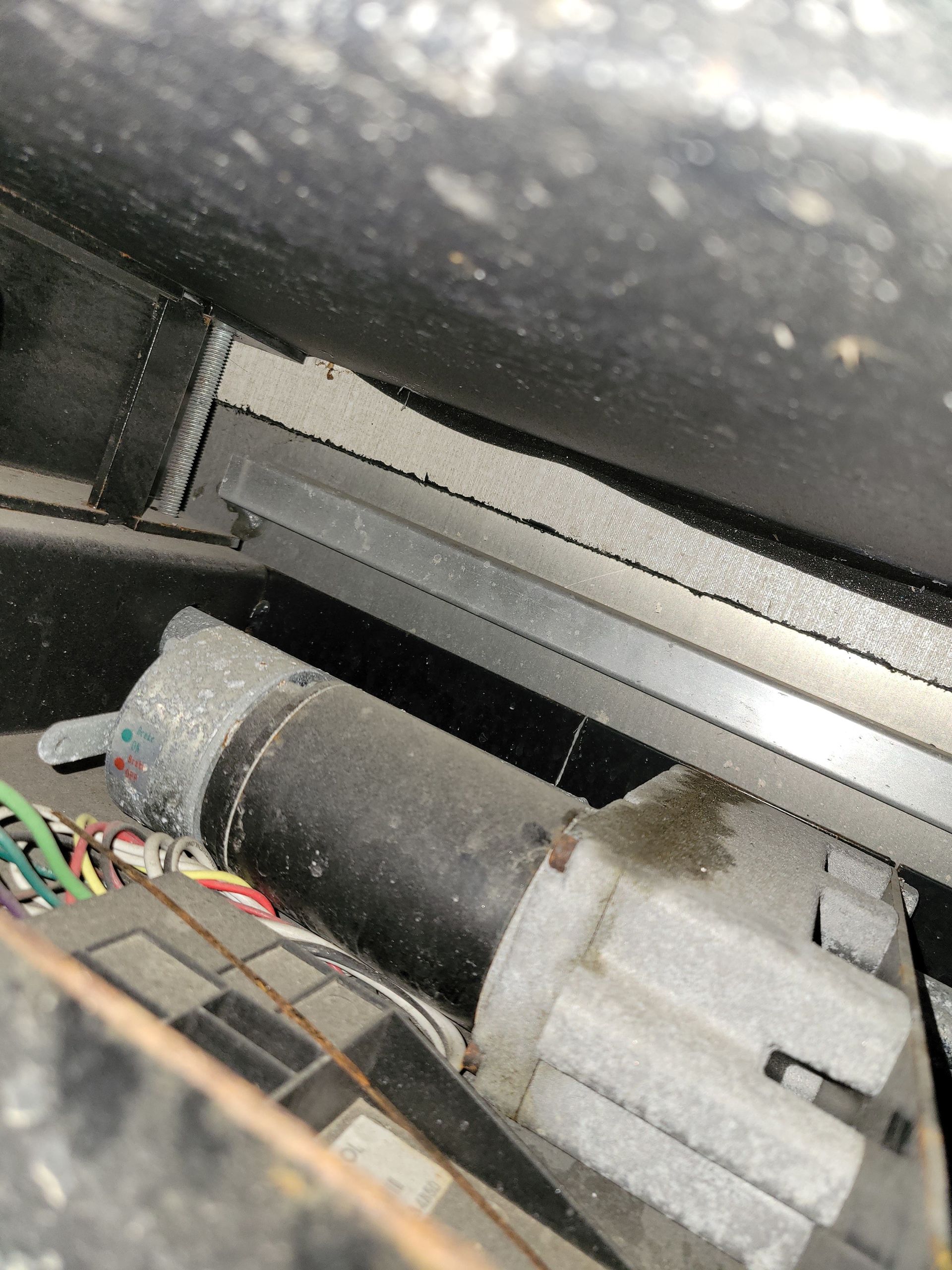 Close-up of a dusty gray electric motor and wiring inside a machine compartment