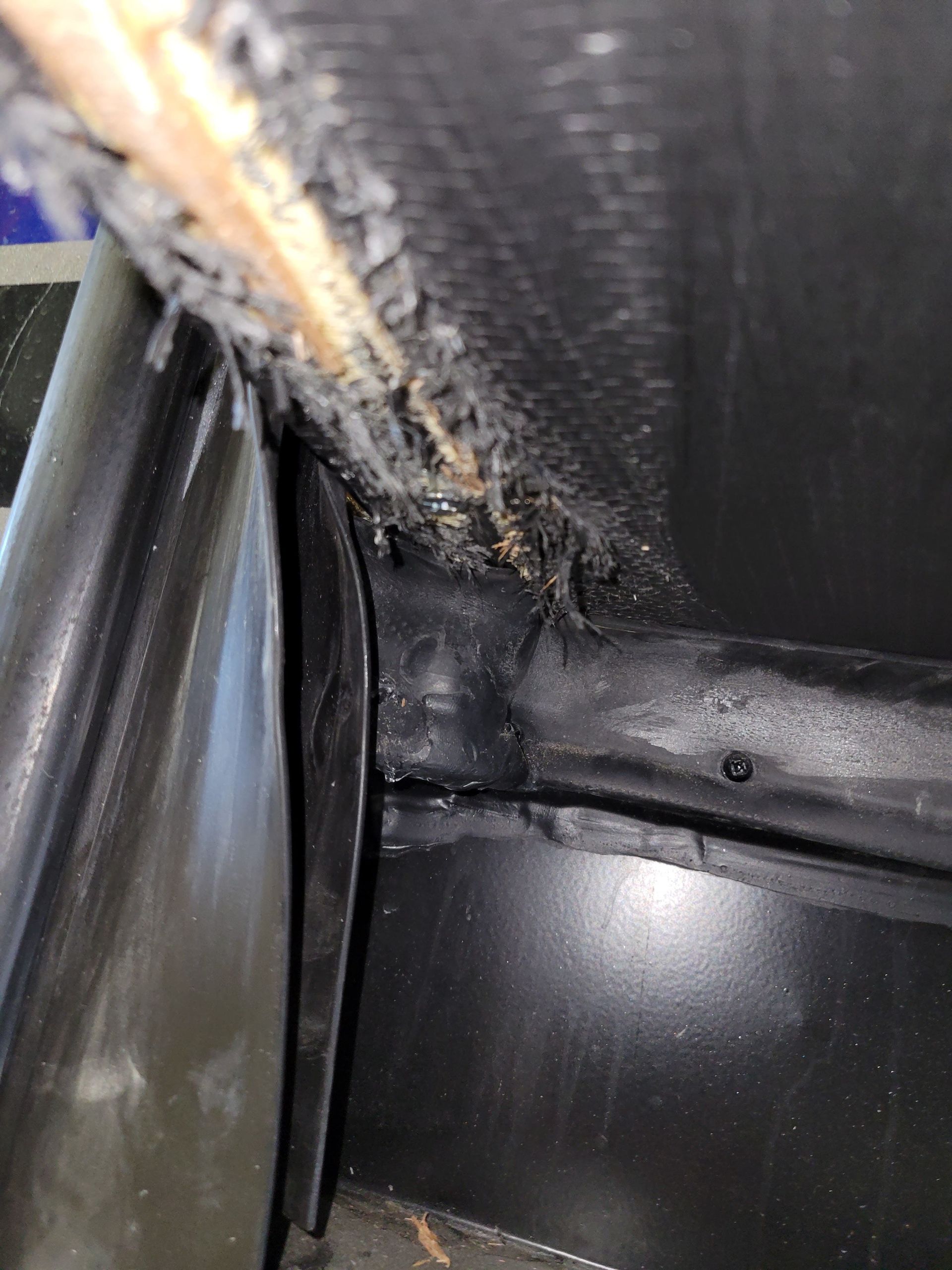 Close-up of a torn black car interior seam with exposed foam and trim damage