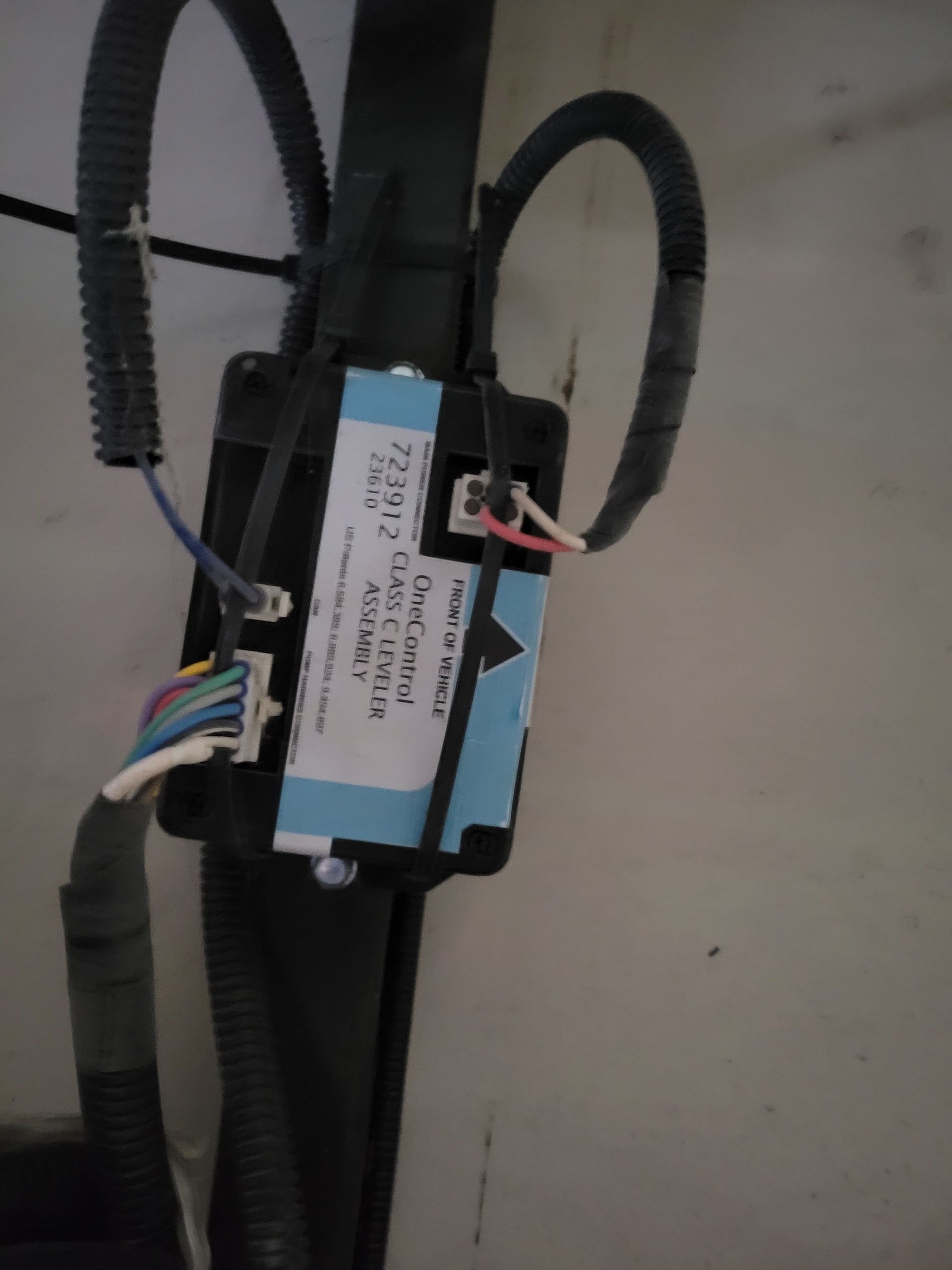 Close-up of a blue and black electronic module with bundled wires on a flat surface