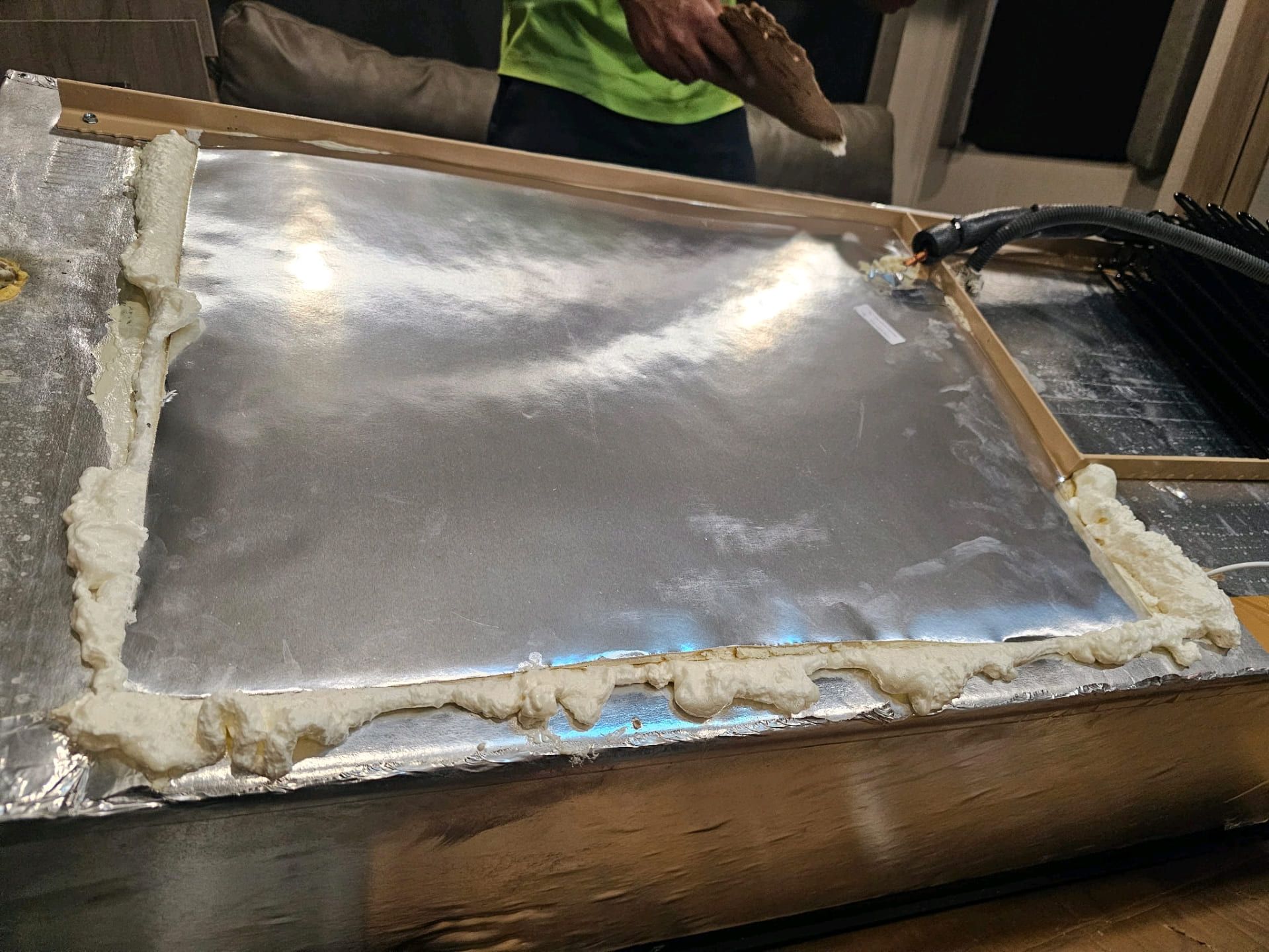 Metal sheet being shaped over a mold in a workshop, with hands visible at the top.