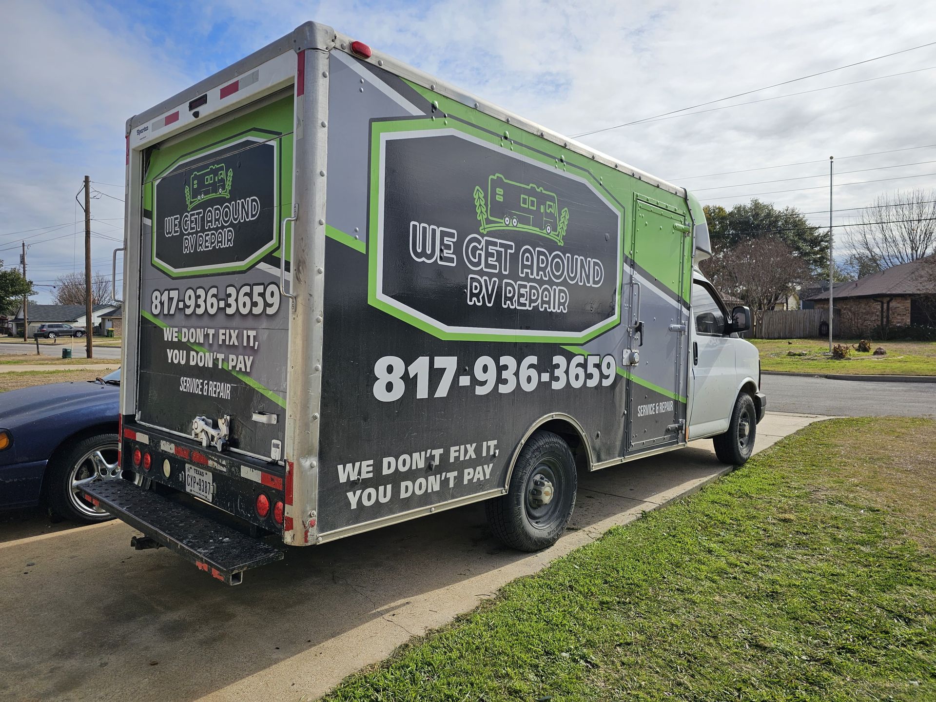 Green and white rental truck parked on a driveway, with large phone number and hauling service ads.
