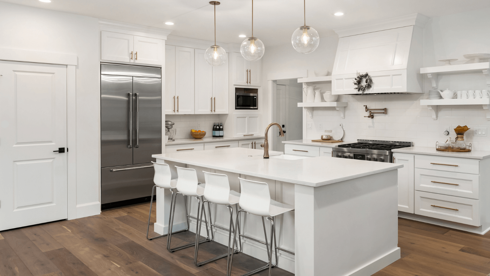 A kitchen with white cabinets , stainless steel appliances , and a large island.
