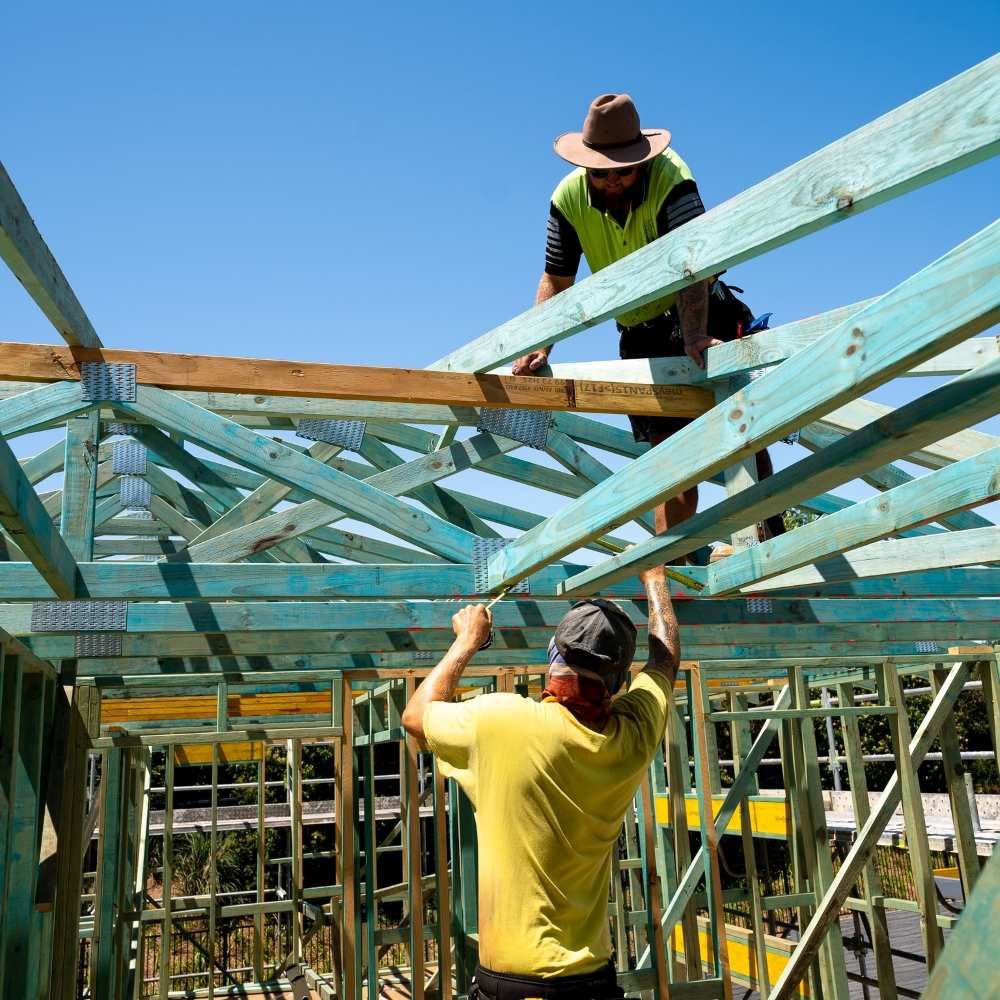 Two Men Are Working On The Wooden Roof Frame Of A House — J.White Carpentry & Renovations in Port Macquarie, NSW