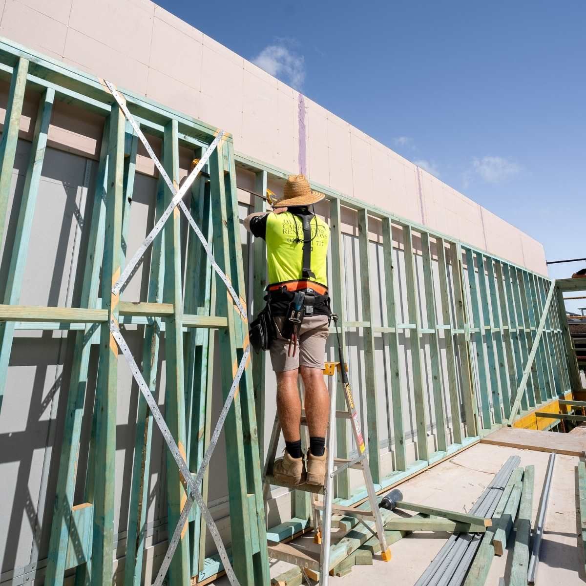 Man Is Standing On A Ladder On Top Of A Home Under Construction — J.White Carpentry & Renovations in Port Macquarie, NSW