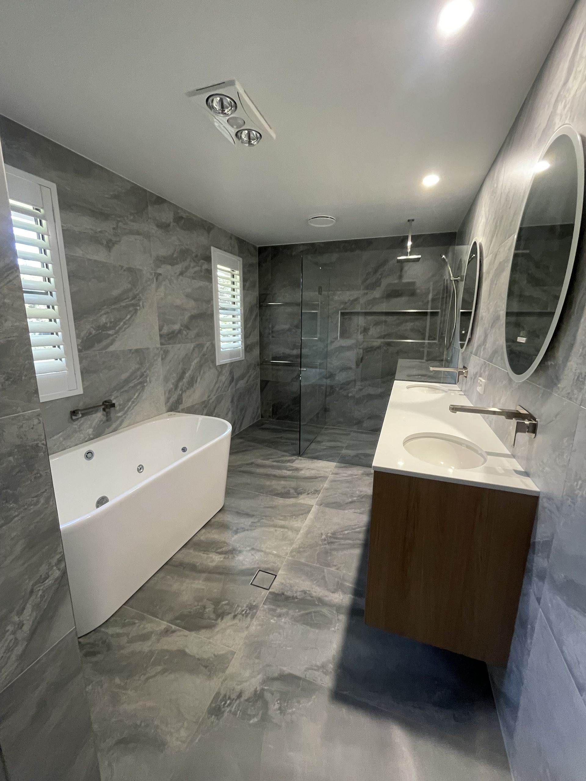 A bathroom with a bathtub , sinks , mirrors and a walk in shower. — J.White Carpentry & Renovations in Port Macquarie, NSW 