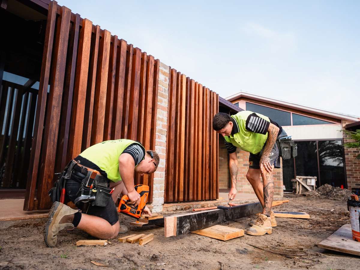 Two Men Are Working On A Wooden Wall — J.White Carpentry & Renovations in Port Macquarie, NSW