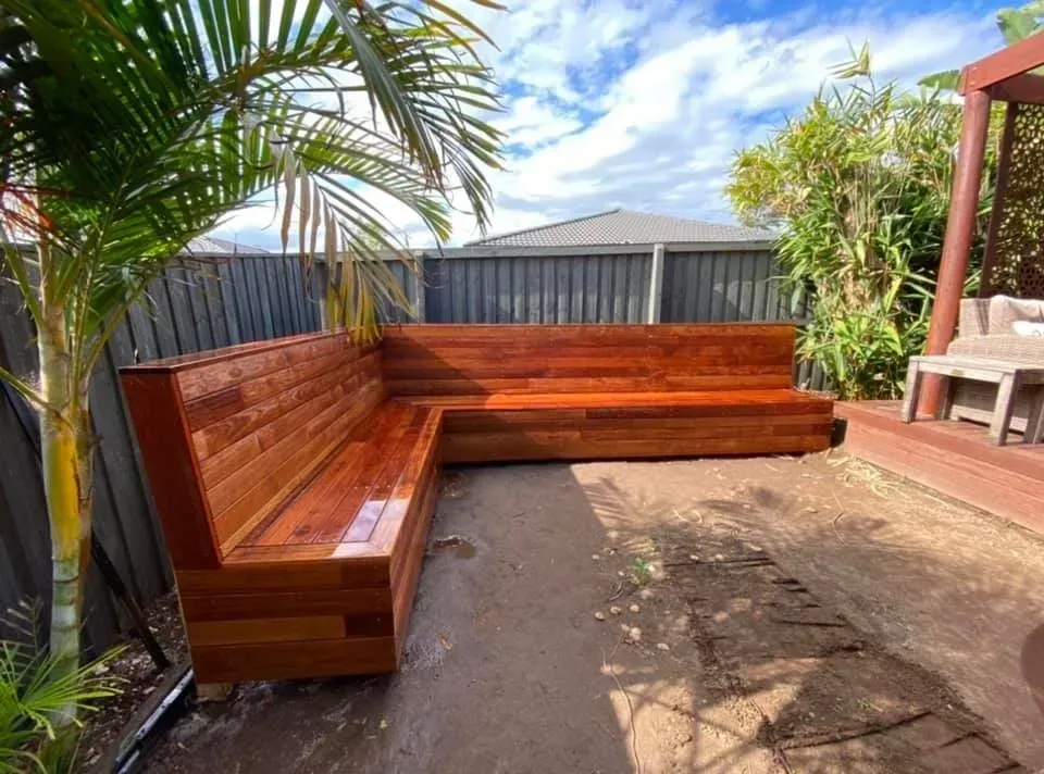 A wooden bench is sitting in a backyard next to a fence. — J.White Carpentry & Renovations in Port Macquarie, NSW