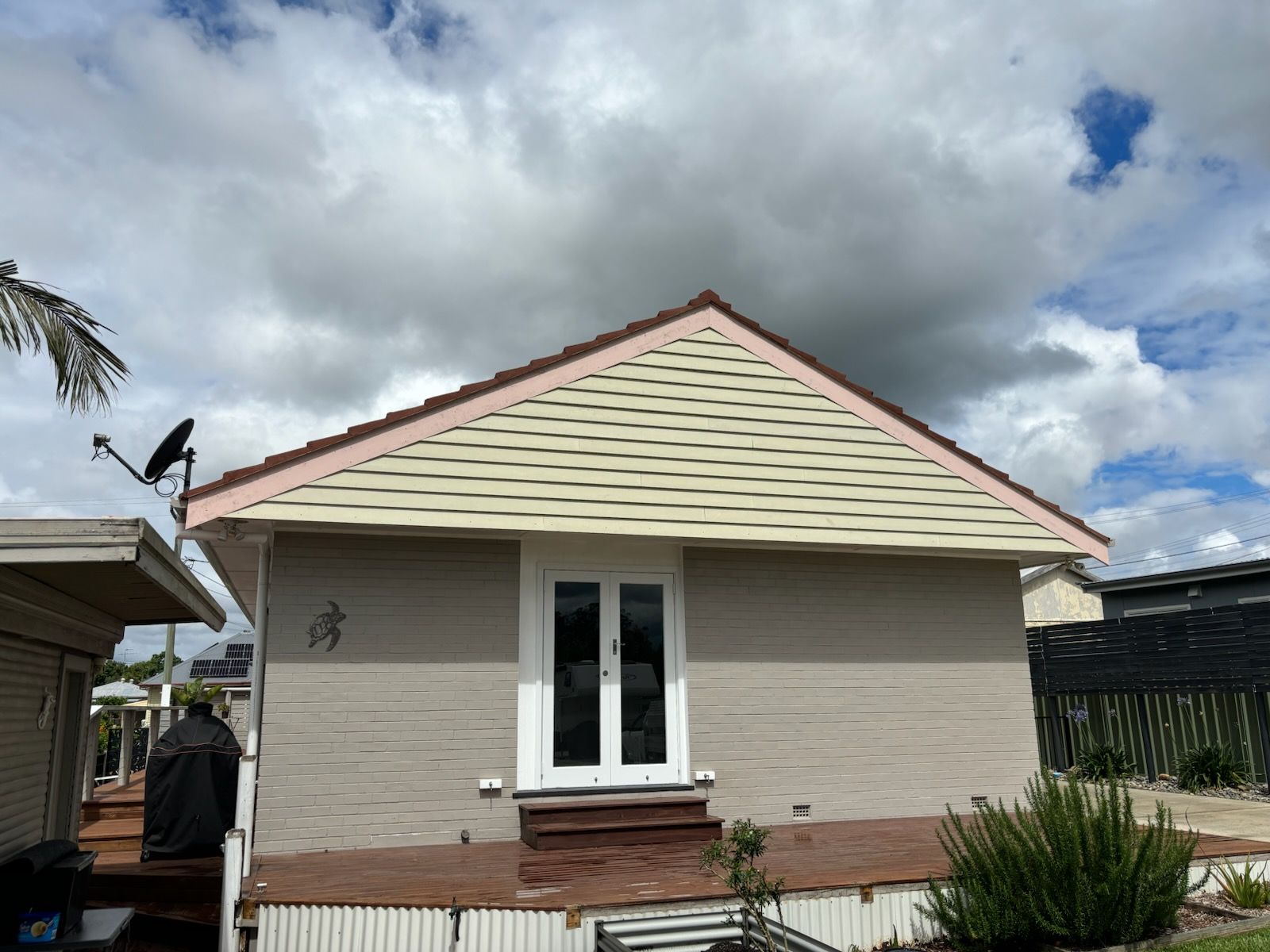 A small house with a pink roof and a satellite dish on the roof. — J.White Carpentry & Renovations in Port Macquarie, NSW 