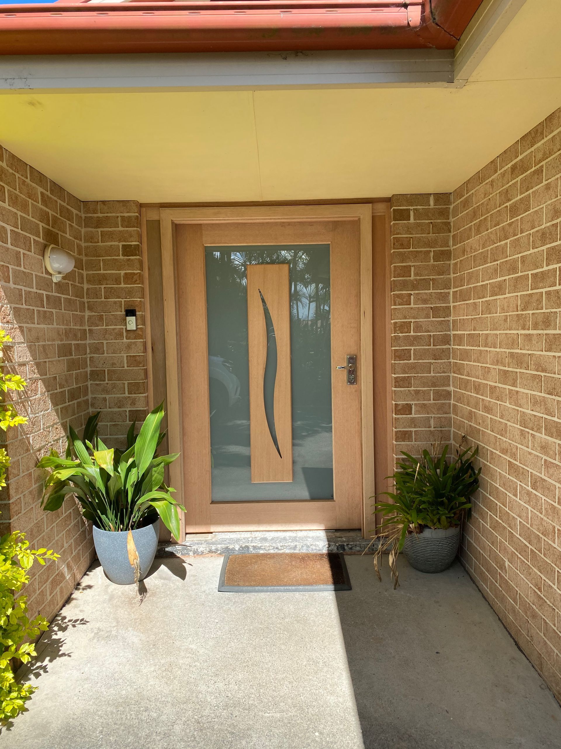 A brick house with a wooden door and a potted plant in front of it. — J.White Carpentry & Renovations in Port Macquarie, NSW