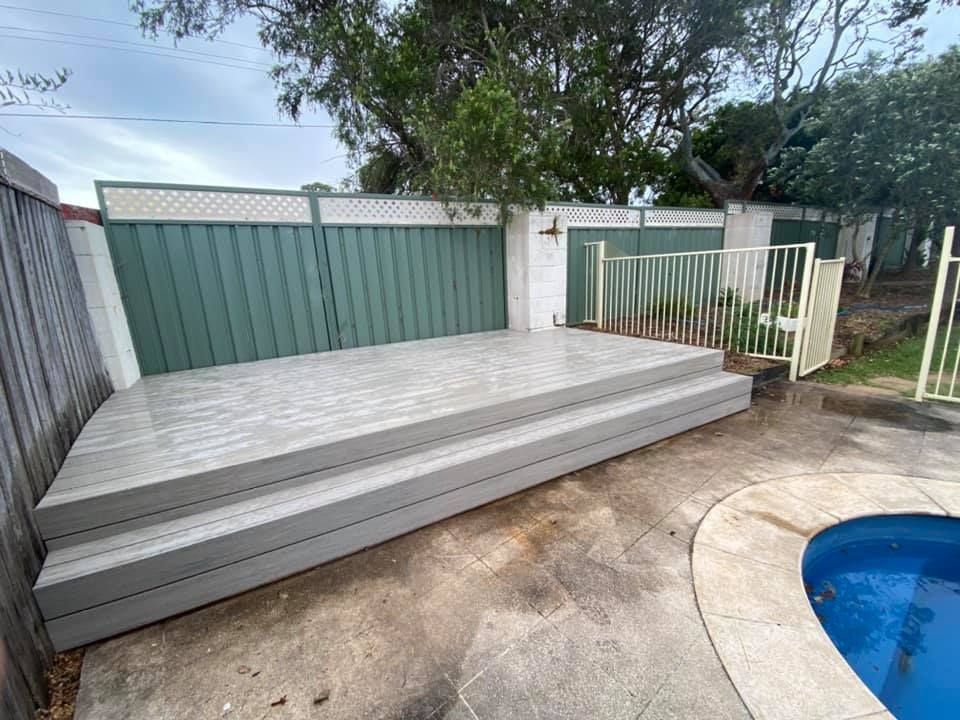 A wooden deck is sitting next to a swimming pool.