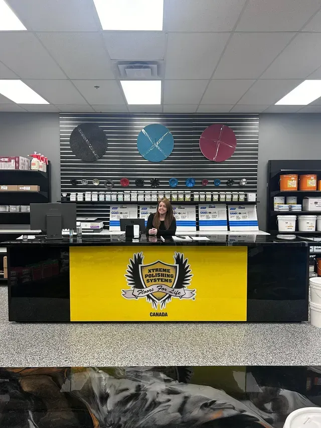 Retail counter with a woman behind a black and yellow display in a shop interior.