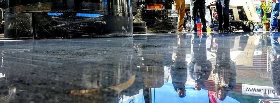 Street scene reflected in a wet sidewalk, with people and buildings mirrored in the puddle.