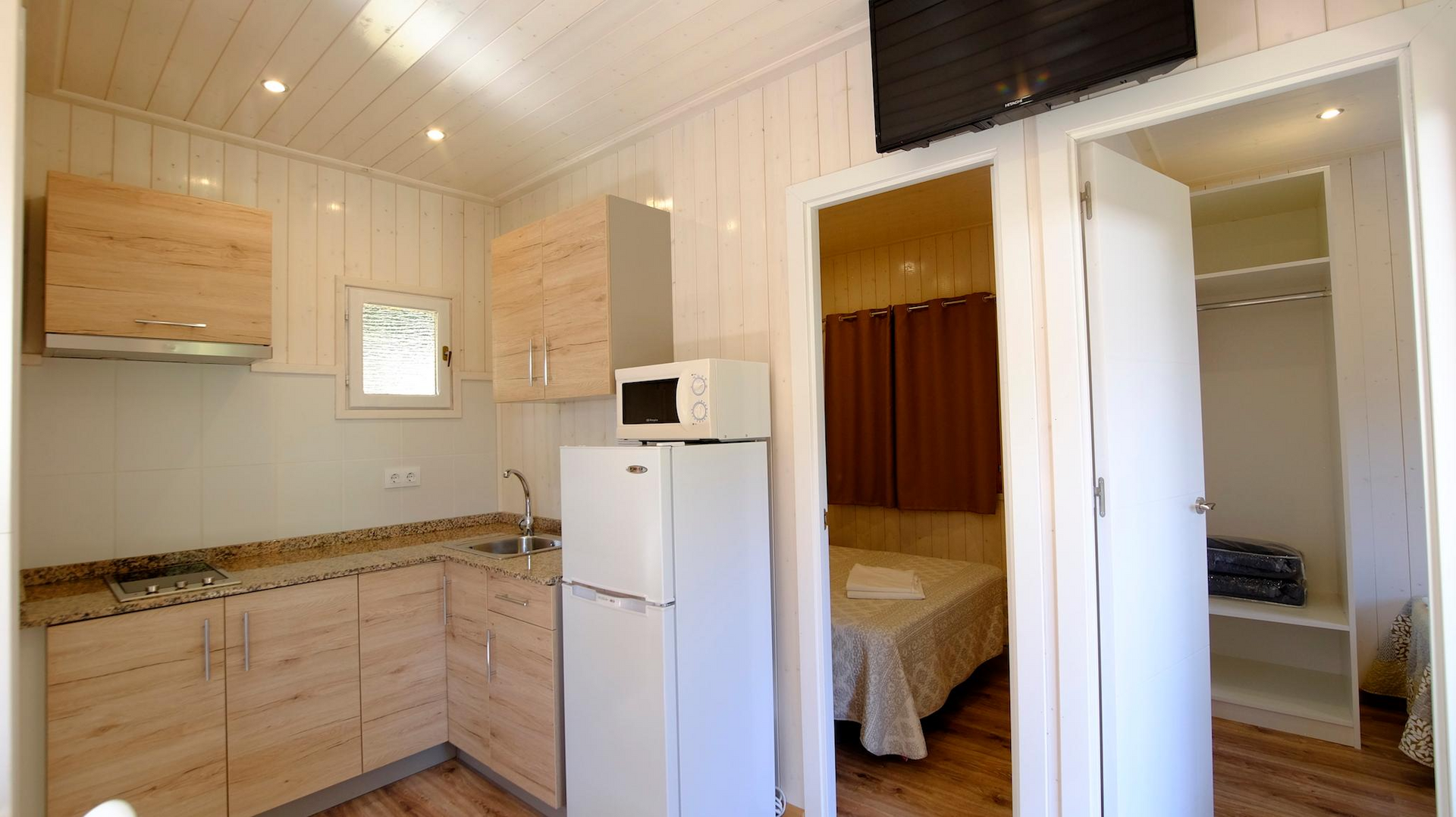 Interior de una pequeña cabaña con cocina, dormitorio y armario.