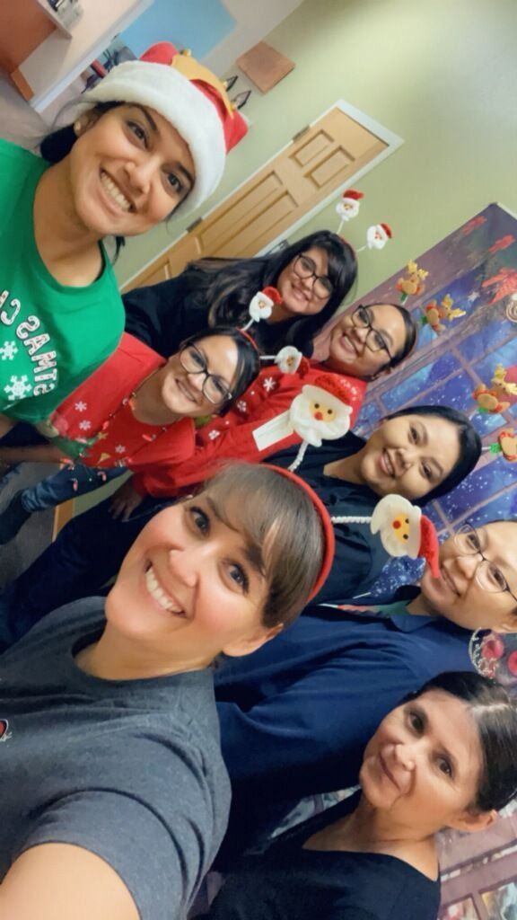 Group of smiling people in holiday attire, posing for a selfie. Festive decorations in background. Group of smiling people in holiday attire, posing for a selfie. Festive decorations in background.
